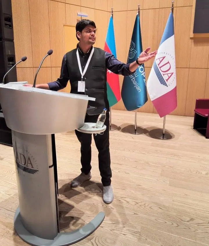 Abhishek speaking from a podium at ADA University during COY19 in Baku, November 2024