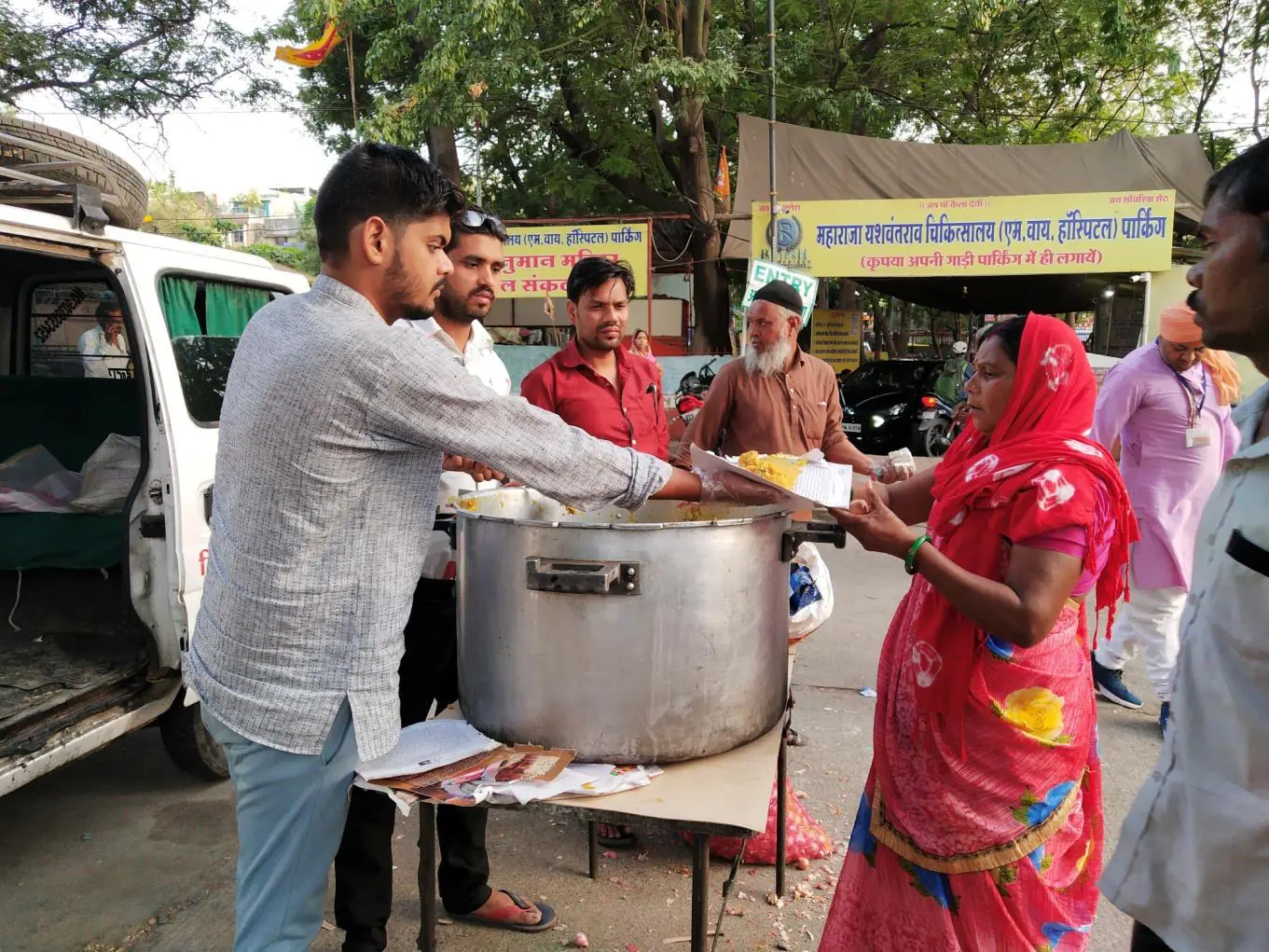 Abhishek serving free meals from a large pot to patients and families at a government hospital in Indore